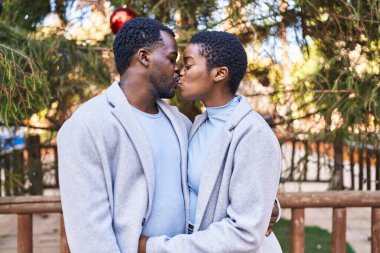 Erkek ve kadın çift parkta sarılıp öpüşüyor.