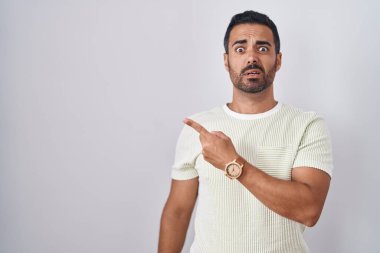 Sakallı İspanyol bir adam izole edilmiş arka planda duruyor. Endişeli, endişeli ve şaşırmış bir ifade takınıyor. 