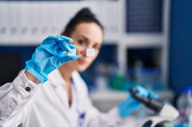 Young caucasian woman scientist using microscope looking sample at laboratory