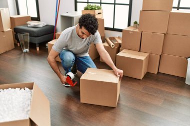 Genç İspanyol adam gülümsüyor yeni evinde mutlu bir paket kutusu var..