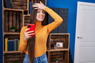 Akıllı telefon kullanan genç esmer kadın. Elleri başının üstünde, şaşırmış ve kızgın bir yüzle stresli. 