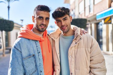 İki erkek caddede birbirlerine sarılıyorlar.