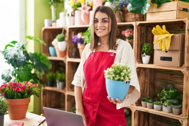 Çiçekçide dizüstü bilgisayar kullanan güzel İspanyol bir çiçekçi.