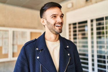 Young hispanic man smiling confident looking to the side at street