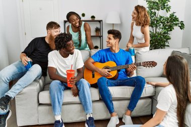 Mutlu gülümseyen ve evde klasik gitar çalan bir grup genç arkadaş..