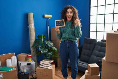 Elinde yeni ev mesajı olan, ağzı açık gülümseyen İspanyol bir kadın. 