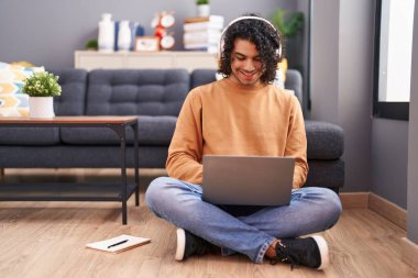 Genç Latin adam evde oturmuş müzik dinliyor.