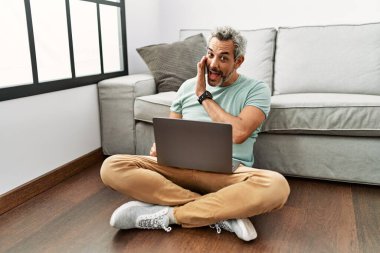 Orta yaşlı İspanyol bir adam diz üstü bilgisayar kullanıyor. Oturma odasında oturuyor. El ele tutuşup gizli dedikodular anlatıyor. 