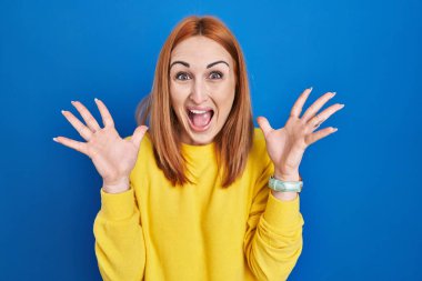 Mavi arka planda durmuş çılgın ve başarısını kutlayan genç bir kadın kollarını kaldırmış ve gözleri açık heyecanlı bir şekilde çığlık atıyor. Kazanan konsept 