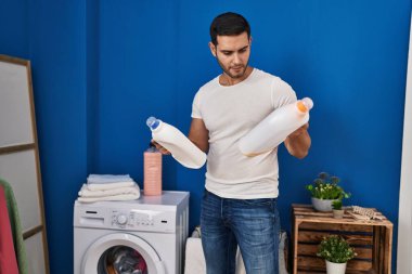 Çamaşır odasında deterjan şişesi tutan genç bir İspanyol.