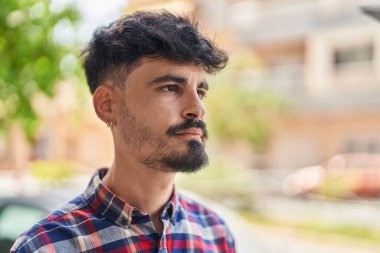 Young hispanic man looking to the side with relaxed expression at street