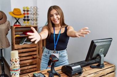 Perakende dükkanında afişi açık tutan esmer bir kadın neşeli gülümseyerek yardım eli uzatıyor ve kabul ediyor.. 