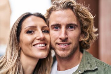 Erkek ve kadın bir arada durarak gülümsüyor.