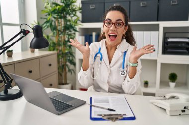Doktor üniforması giyen genç İspanyol kadın ve steteskop deliliği kutluyor ve kollarını kaldırıp heyecanla haykırarak başarı için hayrete düşüyor. Kazanan konsept 