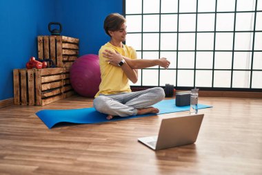 Young caucasian man smiling confident having online stretching class at sport center