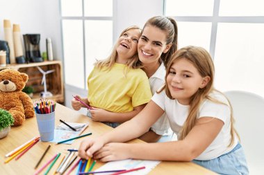Mother and daughters smiling confident drawing at home