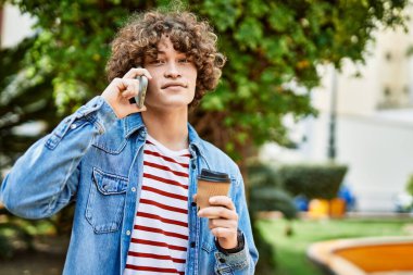 Genç İspanyol adam parkta telefonla konuşuyor.