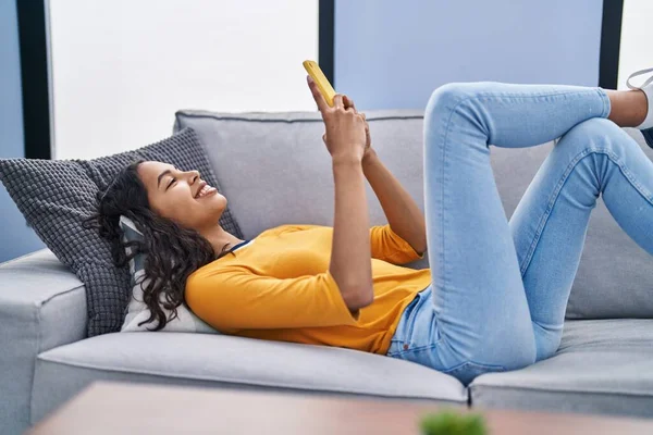 Młoda Afroamerykanka Używa Smartfona Leżącego Kanapie Domu — Zdjęcie stockowe
