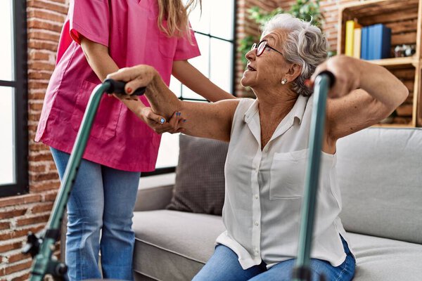 Старшая седовласая пациентка, ухаживающая за медсестрой и ходячей в гериатрическом отделении