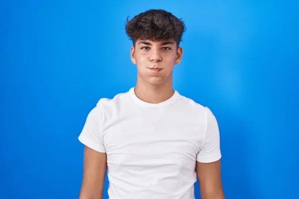 Adolescente Hispânico Sobre Fundo Azul Soprando Bochechas Com Rosto Engraçado — Fotografia de Stock
