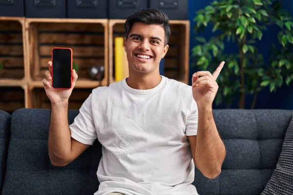 Hispanic Man Håller Smartphone Visar Tom Skärm Ler Glad Pekar — Stockfoto