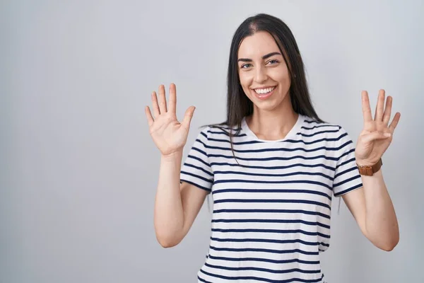 若いですブルネット女性身に着けていますストライプTシャツショーとポイントアップとともに指番号9ながら笑顔自信と幸せ — ストック写真