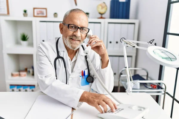 Starszy Siwowłosy Mężczyzna Mundurze Lekarza Rozmawiający Przez Telefon Klinice — Zdjęcie stockowe