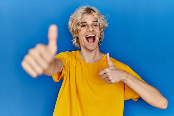 Joven Hombre Moderno Pie Sobre Fondo Azul Aprobando Hacer Gesto —  Fotos de Stock