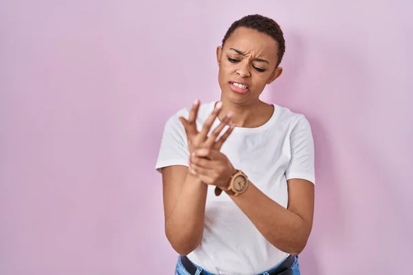 美丽的非洲女人站在粉红的背景上 手指头疼痛 关节炎发炎 — 图库照片