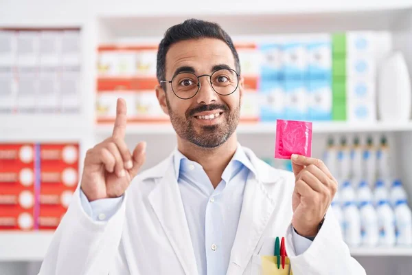 西班牙裔男子 留着胡子 在药店工作 手里拿着避孕套 满脑子都是喜形于色的手指 这让人惊讶不已 — 图库照片