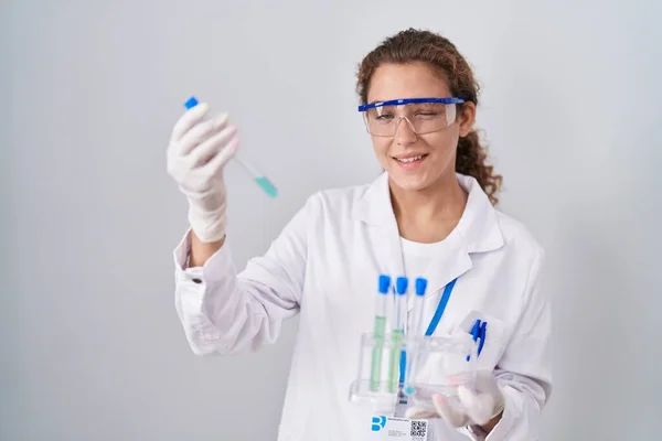Young caucasian scientist woman working with laboratory samples winking looking at the camera with sexy expression, cheerful and happy face.
