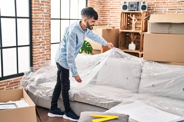 Young Hispanic Man Smiling Confident Unpacking Sofa New Home — Stockfoto