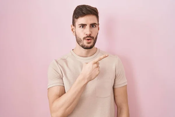 Hispanic Man Beard Standing Pink Background Surprised Pointing Finger Side — Stockfoto
