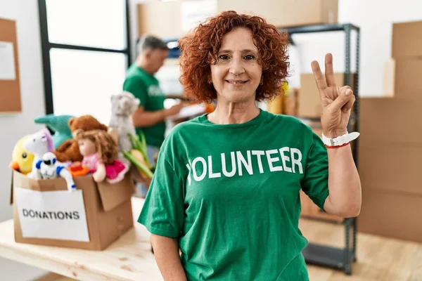 Bağışta Gönüllü Tişört Giyen Orta Yaşlı Bir Kadın Iki Numarayı — Stok fotoğraf