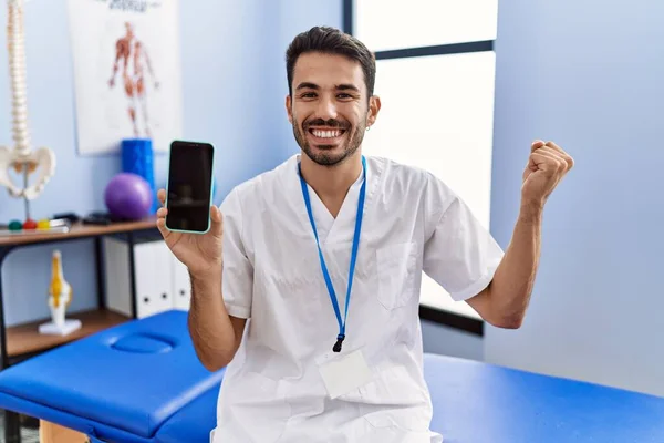 Ung Latinamerikansk Sjukgymnast Man Som Håller Smartphone Kliniken Skriker Stolt — Stockfoto