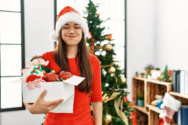 Mulher Morena Jovem Junto Árvore Natal Segurando Decoração Soprando Bochechas — Fotografia de Stock