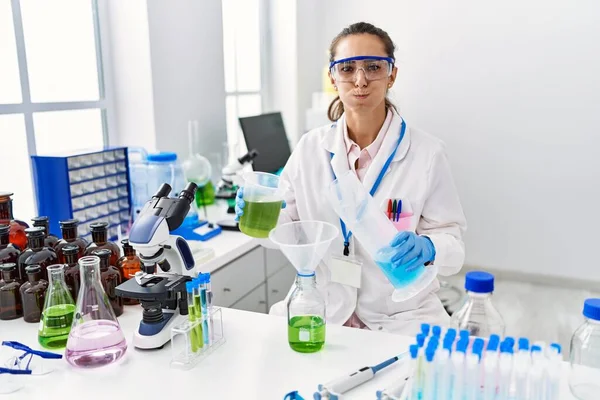 Young Hispanic Woman Working Scientist Laboratory Puffing Cheeks Funny Face — Zdjęcie stockowe