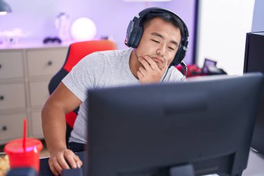 Young chinese man streamer playing video game using computer at gaming room