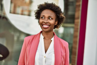 Güzel bir iş adamı Afro saçlı Amerikalı kadın şehirde mutlu ve kendinden emin bir şekilde gülümsüyor.