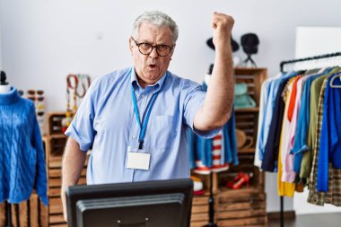 Gri saçlı yaşlı bir adam butikte yönetici olarak çalışıyor kızgın ve kızgın yumruğunu kaldırıyor ve öfkeyle bağırıyor. öfke ve agresif konsept. 