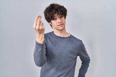 Young man standing over isolated background doing italian gesture with hand and fingers confident expression 