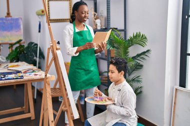 African american mother and son art student and teacher having draw lesson at art studio