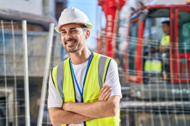 Young hispanic man architect smiling confident standing with arms crossed gesture at street