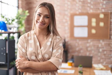 Young caucasian woman business worker standing with arms crossed gesture at office