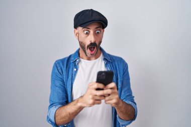 Sakallı İspanyol bir adam akıllı telefondan mesaj yazıyor. Korkmuş ve şok olmuş bir şekilde şaşkınlık ve şaşkınlık içinde.. 