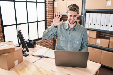 Hispanic man with beard working at small business ecommerce looking positive and happy standing and smiling with a confident smile showing teeth 