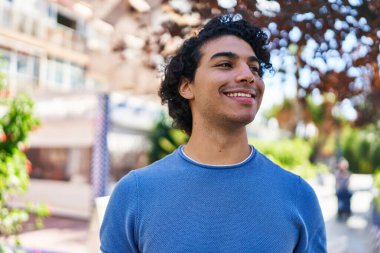 Parkta kendinden emin gülümseyen İspanyol genç adam.