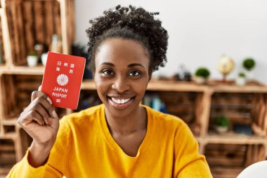 Elinde Japon pasaportu olan Afrikalı Amerikalı bir kadın evdeki masada oturuyor.