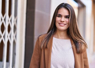 Young beautiful hispanic woman smiling confident looking to the side at street