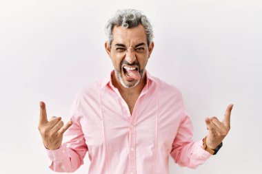 Orta yaşlı İspanyol bir adam izole edilmiş arka planda duruyor çılgın bir ifadeyle bağırıyor elleri havada rock sembolü yapıyor. Müzik yıldızı. ağır kavram. 